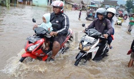   Sejumlah warga nekat melintasi jalan raya yang sudah terendam banjir di Jl Cieunteung, Kecamatan Baleendah, Kabupaten Bandung, Ahad (15/12).  (Republika/Edi Yusuf)