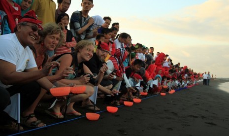 Sejumlah wisatawan asing bersama wisatawan lokal dan anak-anak melepaskan tukik di Pantai Boom, Banyuwangi, Jawa timur, Jumat (14/8). Sebanyak 70 ekor Tukik akan dilepas liarkan dalam rangka menyambut hari kemerdekaan ke 70 RI.