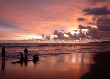 Sejumlah wisatawan bermain air saat matahari terbenam di pantai Palabuhanratu, Sukabumi, Jawa Barat. 