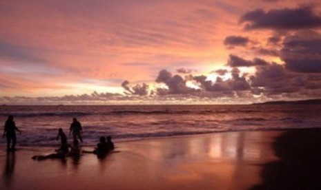 Sejumlah wisatawan bermain air saat matahari terbenam di pantai Palabuhanratu, Sukabumi, Jawa Barat. 