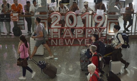 Sejumlah wisatawan membawa barang milik mereka setibanya di Bandara Internasional I Gusti Ngurah Rai, Bali, Kamis (27/12).