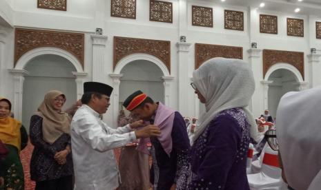 Sekda Bukittinggi Martias Wanto saat mengalungkan tanda pelepasan calon haji. Pemerintah Kota Bukittinggi melepas secara resmi 317 calon haji Kota Bukittinggi tahun 1445 Hijiriyah atau 2024 Masehi, Minggu (19/5/2024). 