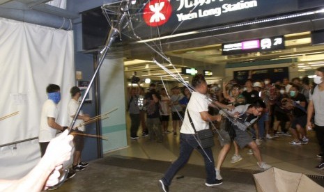 Sekelompok laki-laki berkemeja putih bersenjatakan tongkat logam dan kayu menyerang penumpang di stasiun kereta bawah tanah di New Territory di Hong Kong, Ahad (21/7).