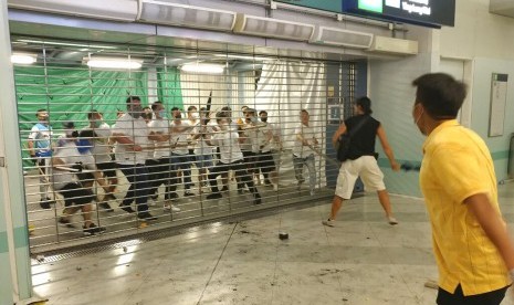 Sekelompok laki-laki berkemeja putih bersenjatakan tongkat logam dan kayu menyerang penumpang di stasiun kereta bawah tanah di New Territory di Hong Kong, Ahad (21/7).