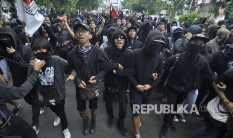 Sekelompok orang mengenakan baju hitam melakukan aksi dengan membakar spanduk dalam rangka may day di Jalan Gazebo, Kota Bandung, Senin (1/5)