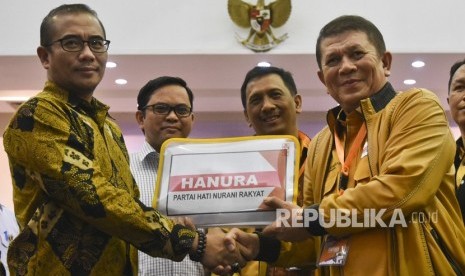 Sekjen Partai Hanura Harry Lontung Siregar (kanan) berjabat tangan dengan Komisioner KPU Hasyim Asy'ari (kiri) disaksikan Wakil Ketua Umum Partai Hanura I Gede Pasek (kedua kanan) dan Komisioner KPU Viryan (kedua kiri) saat menyerahkan berkas pendaftaran bakal calon legislatif di KPU, Jakarta, Selasa (17/7). 