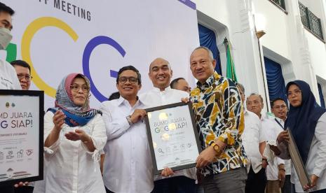 Sekretaris Daerah Provinsi Jawa Barat, Setiawan Wangsaatmaja (kanan batik) bersama Direktur Utama PT Migas Utama Jabar (MUJ) Begin Troys (tengah) menunjukkan piagam Komitmen Terapkan Good Corporate Governance.