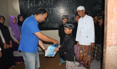 Sekretaris Fordline Club sedang memberikan sebuah bingkisan kepada salah seorang santri Majelis Ar-Ridho.