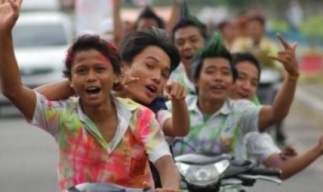 Sekumpulan siswa-siswi SMP berarak-arakan menggunakan motor dengan baju seragam penuh coretan, merayakan kelulusan mereka.