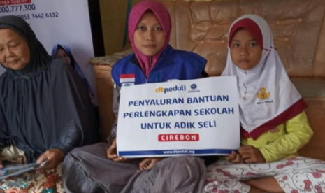 Seli Rahmawati (kanan), siswi kelas 5 SD Impress Cisaat, saat menerima bantuan DT Peduli didampingi oleh neneknya. 