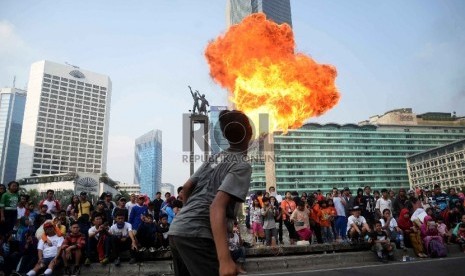  Seniman debus menunjukkan kebolehannya menyemburkan api saat Car Free Day di Bundaran HI, Jakarta, Ahad (14/6).  (Republika/Yasin Habibi)