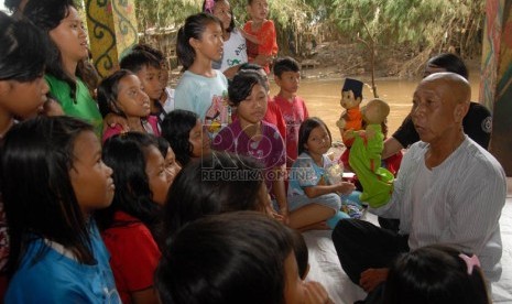 Seniman Pak Ogah menghibur sejumlah anak korban banjir di Sanggar Ciliwung Bukit Duri, Jakarta, Sabtu (26/1). (Republika/Agung Fatma Putra)