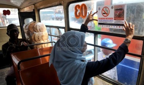  Seorang aktivis Koalisi Warga Untuk Jakarta Bebas asap Rokok (Smoke Free Jakarta) menempelkan stiker penanda larangan merokok di angkutan umum di Terminal Senen Jakarta. (Republika/Prayogi)