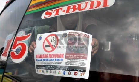  Seorang aktivis Koalisi Warga Untuk Jakarta Bebas asap Rokok (Smoke Free Jakarta) menempelkan stiker penanda larangan merokok di angkutan umum di Terminal Senen Jakarta, Selasa (21/5).    (Republika/Prayogi)