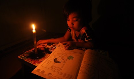 Seorang anak belajar dengan bantuan penerangan lilin saat terjadi pemadaman listrik di Palu, Sulawesi Tengah, Jumat (11/3). 