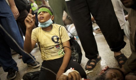 Seorang anak berdiri di atas lututnya sambil berdoa di samping ayahnya yang tewas, dalam bentrokan pendukung Presiden Mursi dengan pasukan keamanan di Nasr City, Kairo, Sabtu (27/7).    (AP/Manu Brabo)