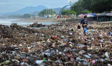 Seorang anak berjalan di atas tumpukan sampah plastik yang berserakan di Pantai Padang, Sumatera Barat, Selasa (22/1/2019). 