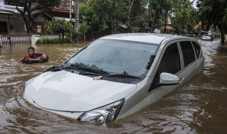 Seorang anak bermain air di dekat mobil yang terendam banjir di RT 001 RW 02 Kelurahan Bukitduri, Tebet Jakarta, Kamis (16/2).