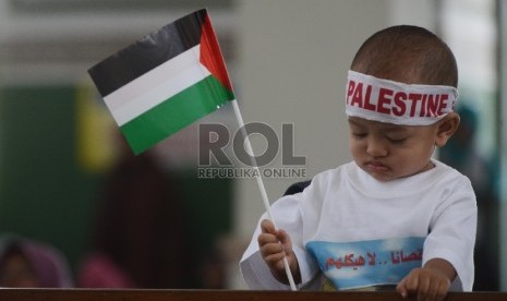 Seorang anak bermain bendera Palestina saat penandatanganan surat pernyataan bersama yang diasosiakan oleh Asia Pasific Comunity for Palestine (ASPAC) usai Shalat Jumat bersama di Masjid Al Azhar, Jumat (17/9). 