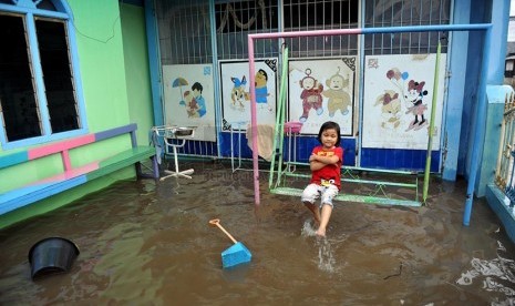   Seorang anak bermain saat banjir merendam perumahan Jatikramat Indah di Bekasi, Jawa Barat, Jumat (28/3). (Republika/Edwin Dwi Putranto)