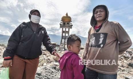 Seorang anak bersama orang tuanya mencari kerabatnya yang menjadi korban gempa dan tsunami di Balaroa, Palu, Sulawesi Tengah, Kamis (4/10).