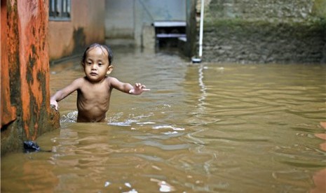 Seorang anak berusaha melintasi genangan banjir. (ilustrasi) 