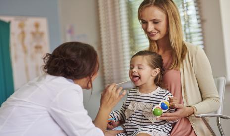 Seorang anak diperiksa amandelnya oleh dokter.