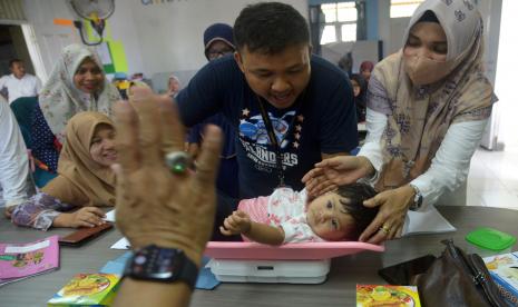 Seorang anak ditimbang saat berlangsung bulan imunisasi, termasuk imuniasi campak. (Ilustrasi)