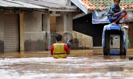  Seorang anak duduk di atas boks telepon umum sambil melihat genangan air banjir di Jalan Kampung Melayu Kecil,Jakarta Timur, Selasa ( 5/3).  (Republika/Prayogi)