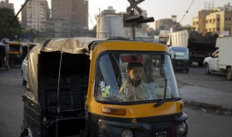 Seorang anak duduk di atas tuk-tuk di daerah kumuh Kairo, Mesir, Rabu (4/12). Pemerintah Mesir berencana menghapus tuk-tuk dan menggantinya dengan minivan.