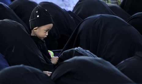 Seorang anak jamaah An Nadzir bermain di dekat ibunya saat melakukan salat Idul Adha di Kampung Jamaah An Nadzir, Danau Mawang Gowa, Sulawesi Selatan, Selasa (22/9).