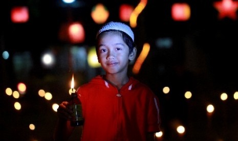 Seorang anak kecil memegang lampu botol saat perayaan tradisi Tumbilotohe (malam pasang lampu) di Limboto, Kabupaten Gorontalo.