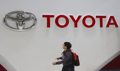 Seorang anak laki-laki melintas di depan logo Toyota di Tokyo, Rabu (15/1). Toyota melaporkan kinerja perusahaannya yang turun akibat pandemi Covid-19.