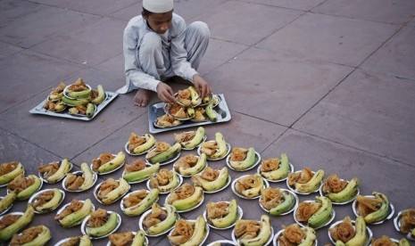 Seorang anak laki-laki menyiapkan iftar bagi jamaah di Masjid Jama, Delhi, India.