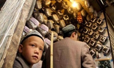 PBNU Nilai Persoalan Uighur seperti Separatis di Papua. Foto: Seorang anak laki-laki Xinjiang membantu ayahnya berjualan peci khas Muslim Uighur.