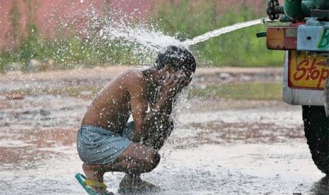 Seorang anak mandi di tengah suhu udara ekstrem yang mencapai 50 derajat Celsius di India sepekan terakhir.