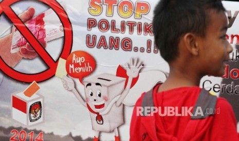 Seorang anak melintas di depan poster Stop Politik Uang.  (ilustrasi)