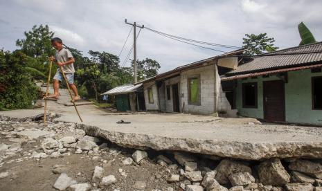 Seorang anak melintas di jalan yang terbelah akibat pergerakan tanah di Bojong Koneng, Babakan Madang, Kabupaten Bogor, Jawa Barat. Pemkab Bogor segera akan mencairkan dana sewa rumah untuk korban pergeseran tanah.