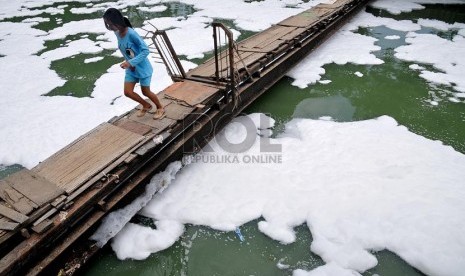   Seorang anak melintasi jembatan Kali Sunter yang dipenuhi busa dari Rumah Pompa Sunter Selatan, Jakarta Utara, Rabu (27/11).   (Republika/Prayogi) 