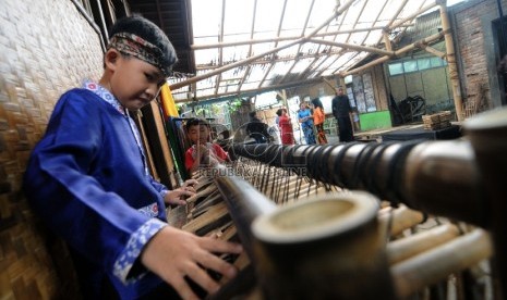 Seorang anak memainkan angklung toel di saung angklung Ujo, Padasuka, Kota Bandung, Selasa (12/2). 