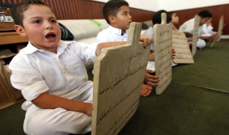 Seorang anak membaca sebuah papan tulis kayu sambil menghafal Alquran di Tripoli, Libya, Senin (23/7).   (Ismail Zitouny/Reuters)