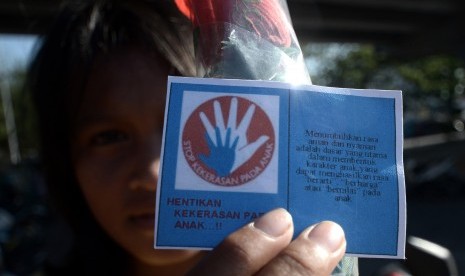 Seorang anak memegang kertas berisi himbauan memperingati Hari Anak Nasional 2015 di bawah jembatan layang, Makassar, Sulawesi Selatan, Kamis (23/7).