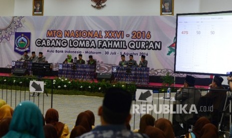 Seorang anak memotret tiga grup Kafilah yang mengikuti final MTQ Nasional ke XXVI cabang Fahmil Quran (Cerdas Cermat) di Aula Bank Indonesia, Kota Mataram, Nusa Tenggara Barat, Kamis (4/8).