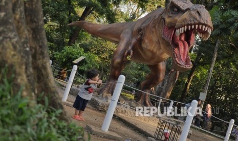 Seorang anak memperhatikan patung dinosarus T-Rex di Taman Lansia Bandung, Selasa (2/8).