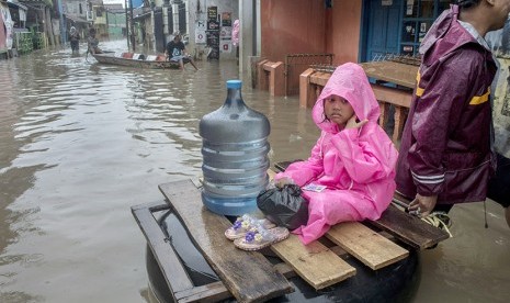 Seorang anak menaiki ban saat melintasi banjir di kawasan Baleendah, Kabupaten Bandung, Jawa Barat.