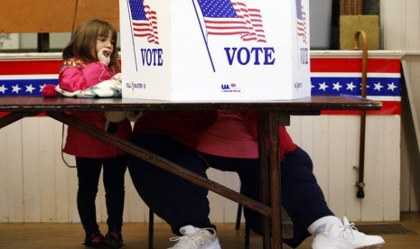   Seorang anak menengok neneknya (tidak terlihat) tengah memberikan suaranya dalam TPS (tempat pemungutan suara) di balaikota Bristol, New Hampshire (6/11).   (Reuters/Jessica Rinaldi)  