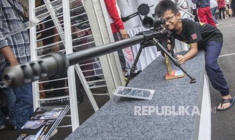 RUU Ciptaker Diharap Bisa Kembangkan Industri Pertahanan. Foto ilustrasi: Seorang anak meneropong menggunakan senjata api laras panjang yang ditampilkan dalam Pameran Industri Pertahanan di Lapangan Bhineka Tunggal Ika, kompleks Kementerian Pertahanan (ilustrasi).