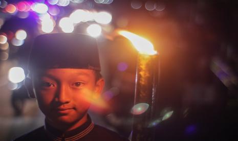 Seorang anak mengikuti pawai obor di Jalan Raya Puncak, Ciawi, Kabupaten Bogor, Jawa Barat, Jumat (29/7/2022). Pawai obor tersebut untuk menyambut Tahun Baru Islam 1 Muharram 1444 Hijriah. Sambut Tahun Baru Islam, Warga Sukabumi Ikuti Istigatsah dan Sujud Syukur