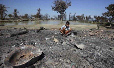  Seorang anak mengumpulkan potongan logam dari puing perkampungan Pauktaw yang dibakar dalam kekerasan baru-baru ini di Rakhine,Myanmar, Sabtu (27/10). (Soe Zeya Tun/Reuters) 