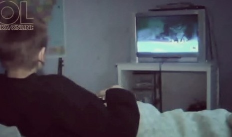 Seorang anak menonton acara televisi di kamar tidur